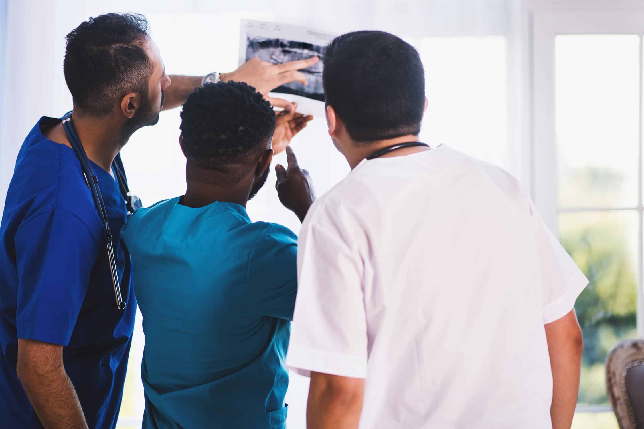 Dentiste qui examine une radio de la mâchoire de son patient avant de lui poser un implant dentaire